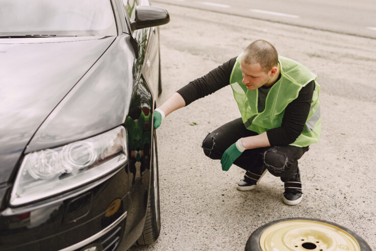 Driver inspecting possible hidden damage near the front wheel area after a car accident