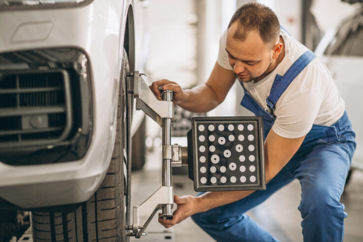 Collision repair technician checking wheel alignment on a vehicle